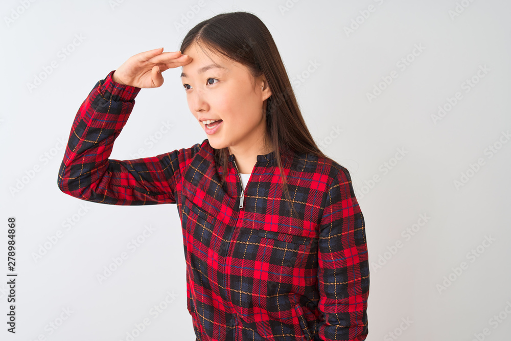 Young chinese woman wearing casual jacket standing over isolated white background very happy and smiling looking far away with hand over head. Searching concept. Young chinese woman wearing casual jacket standing over isolated white background very happy and smiling looking far away with hand over head. Searching concept.