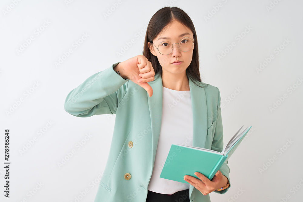 Young chinese student woman wearing glasses reading book over isolated white background with angry face, negative sign showing dislike with thumbs down, rejection concept Young chinese student woman wearing glasses reading book over isolated white background with angry face, negative sign showing dislike with thumbs down, rejection concept