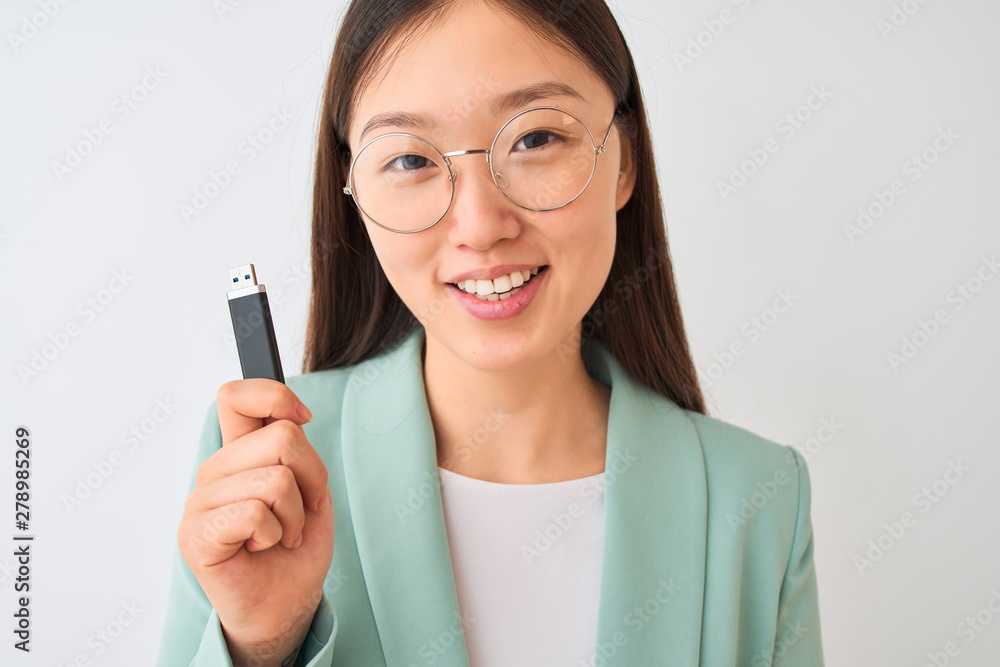 Young chinese businesswoman holding usb memory over isolated white background with a happy face standing and smiling with a confident smile showing teeth Young chinese businesswoman holding usb memory over isolated white background with a happy face standing and smiling with a confident smile showing teeth