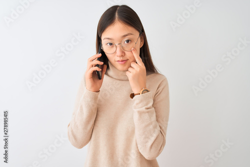 Fotografie Young chinese woman talking on the smartphone over isolated white background Poi