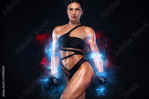 Fototapeta Naklejka Na Ścianę i Meble -  Strong muscular bodybuilder athletic woman pumping up muscles with dumbbells on black background. Workout bodybuilding and energy concept.