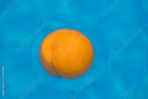 composition of colors with an orange peach floating in the water with a blue background photo