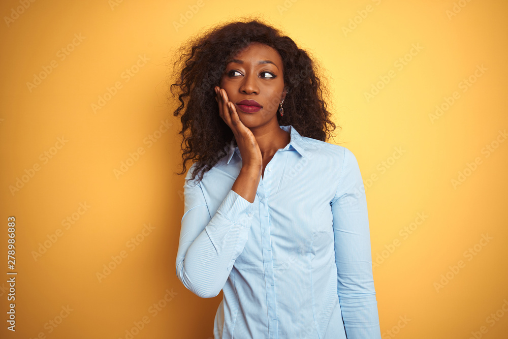 African american businesswoman wearing elegant shirt over isolated yellow background thinking looking tired and bored with depression problems with crossed arms. African american businesswoman wearing elegant shirt over isolated yellow background thinking looking tired and bored with depression problems with crossed arms.