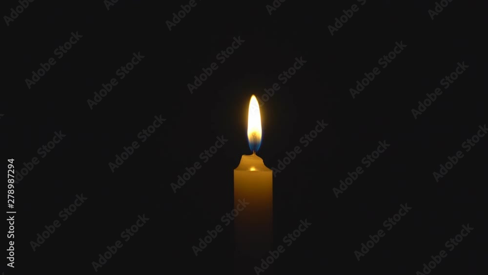 A single white candle burning. Looping for use as a background or illustration of remembrance or celebration. The wind tries to put out the flame, but it recovers each time. The eternal flame.