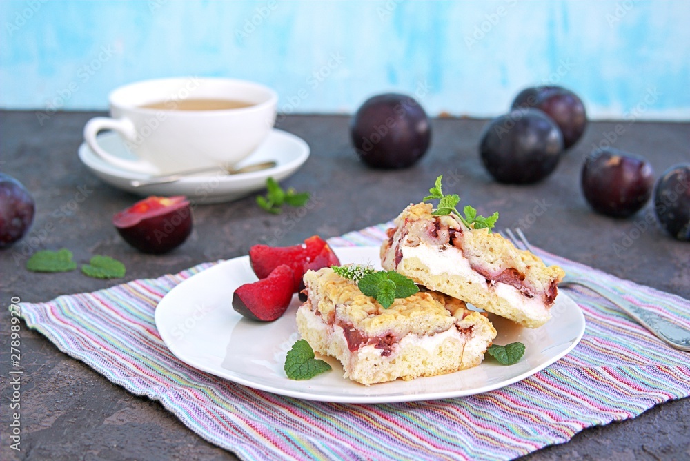 Sliced shortbread cake with curd cream and plum on a white plate. Sweet cakes. Harvest plums. Sliced shortbread cake with curd cream and plum on a white plate. Sweet cakes. Harvest plums.