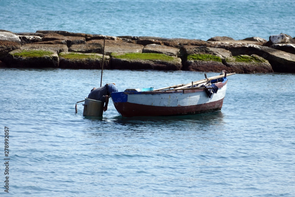 Pescatore sulla barca mentre perlustra il fondale del mare dentro uno scafandro artigianale. Sud Italia Pescatore sulla barca mentre perlustra il fondale del mare dentro uno scafandro artigianale. Sud Italia