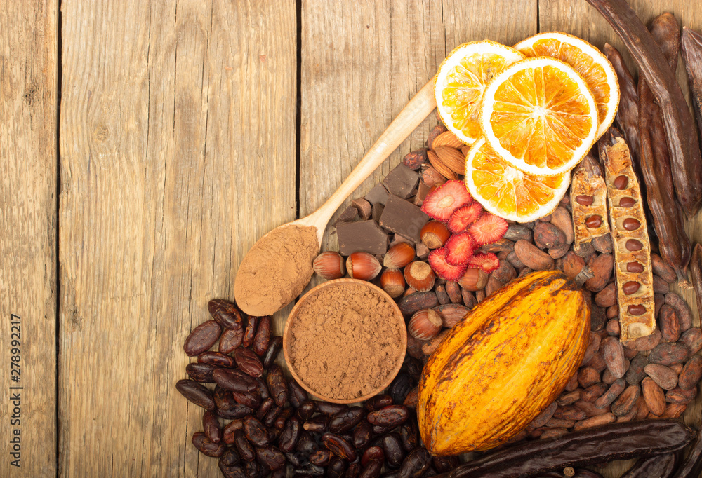 cacao pods, carob pods and dried fruits on wooden background