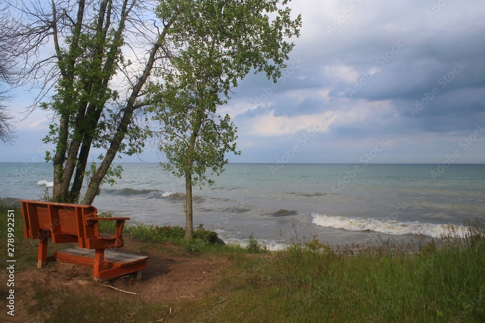 Beautiful summer landscape in a state park. Lake Michigan scenic view with wooden bench on the beach at the Harrington Beach State Park, Wisconsin, USA. Wisconsin nature background.