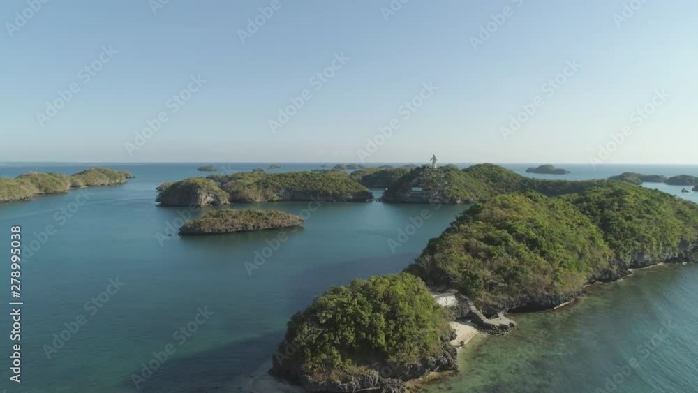 Small islands in Hundred Islands National Park with statue of Jesus Christ, Pangasinan, Philippines. Aerial view of group of small islands with beaches and lagoons, famous tourist attraction, Alaminos Small islands in Hundred Islands National Park with statue of Jesus Christ, Pangasinan, Philippines. Aerial view of group of small islands with beaches and lagoons, famous tourist attraction, Alaminos