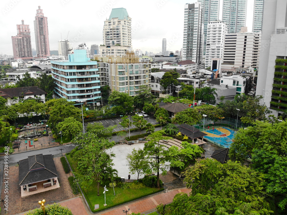 Obraz premium Aerial view Benchasiri Park next Sukhumvit street, Bangkok, Thailand. Aerial view of Bangkok Benchasiri Park with little lake and skyscraper on the background.