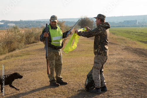 Hunters with a german drathaar and spaniel, pigeon hunting with dogs in reflective vests 