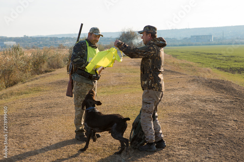 Hunters with a german drathaar and spaniel, pigeon hunting with dogs in reflective vests 