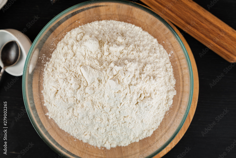 Making dough for pizza, flour in glass bowl on wooden cutting board, top view Making dough for pizza, flour in glass bowl on wooden cutting board, top view