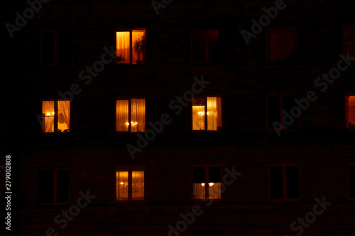 Illuminated in the dark of the night the windows of the houses of an apartment house