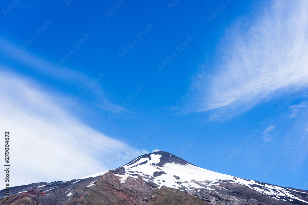 Top center of the Villarica volcano with snow and smoke One of the most active volcanoes in the area.
