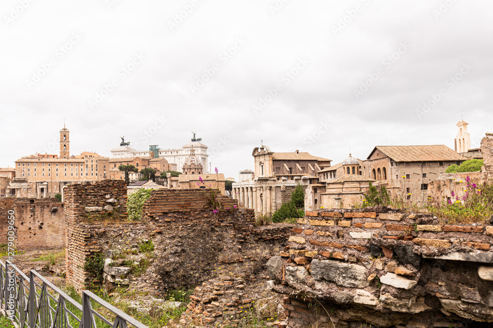 buildings and ruined bricked walls under grey sky in rome, italy