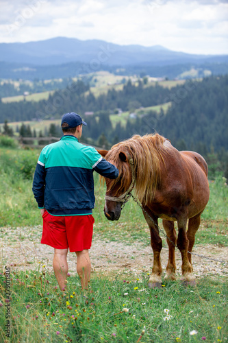man near horse in field mountains on background