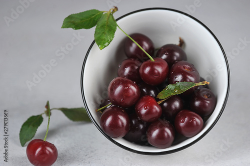 Ripe berries of sweet cherry in a white bowl. Light background. Close-up.