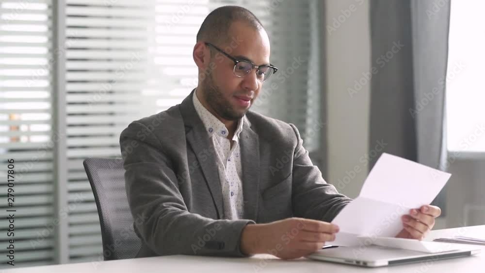 Happy african businessman read mail letter excited by good news Happy african businessman read mail letter excited by good news