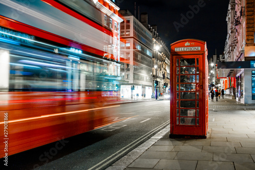 Light trails of a double decker bus next to the iconic telephone booth in London