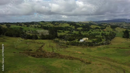 Aerial flyover view of remote houses in green rolling landscape / Towai, New Zealand photo