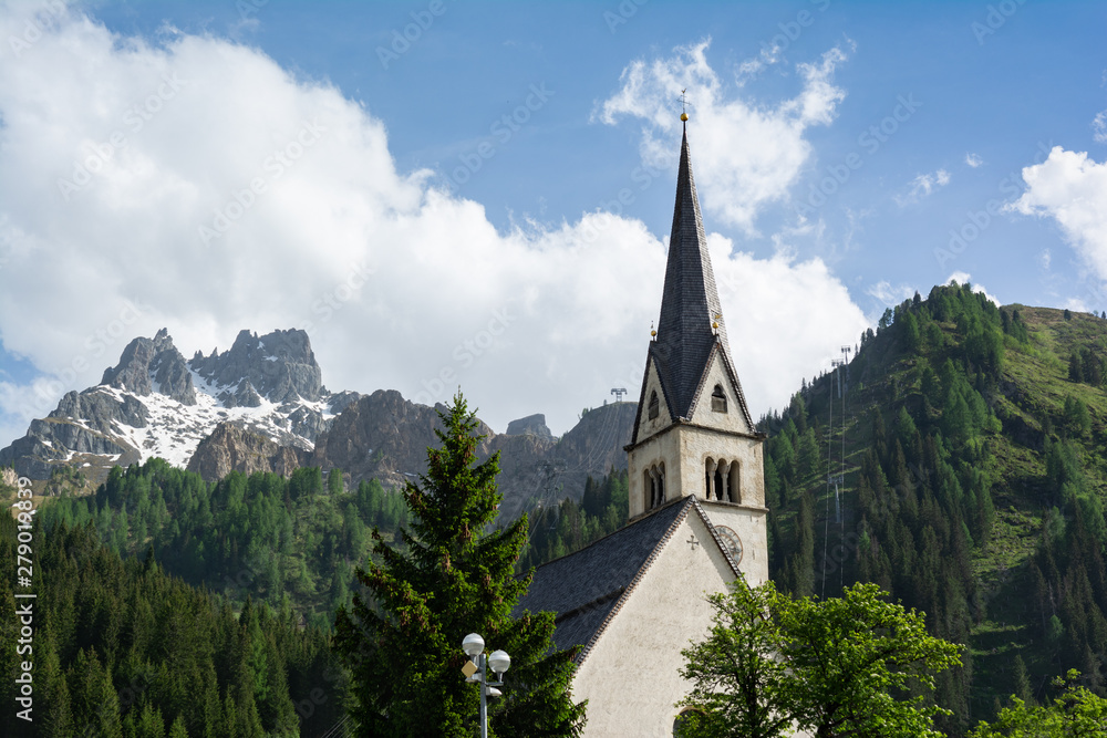 Catholic church in Arabba village with cable car Porta Vescovo on the background. Trentino, Italy
