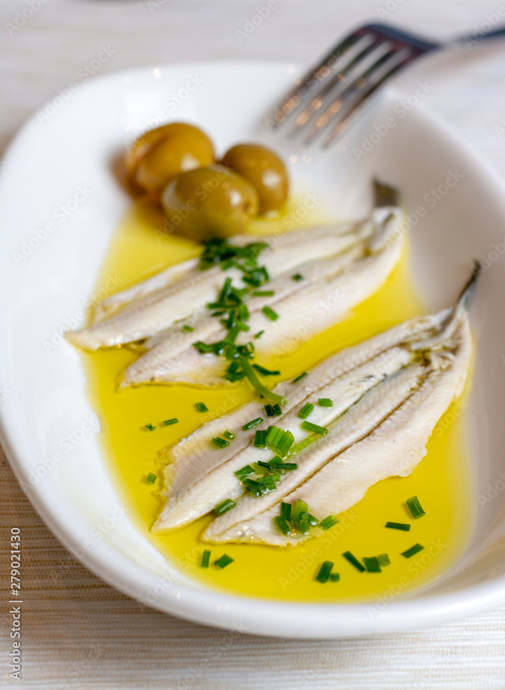 Anchovies marinated in vinegar with olive oil and parsley.