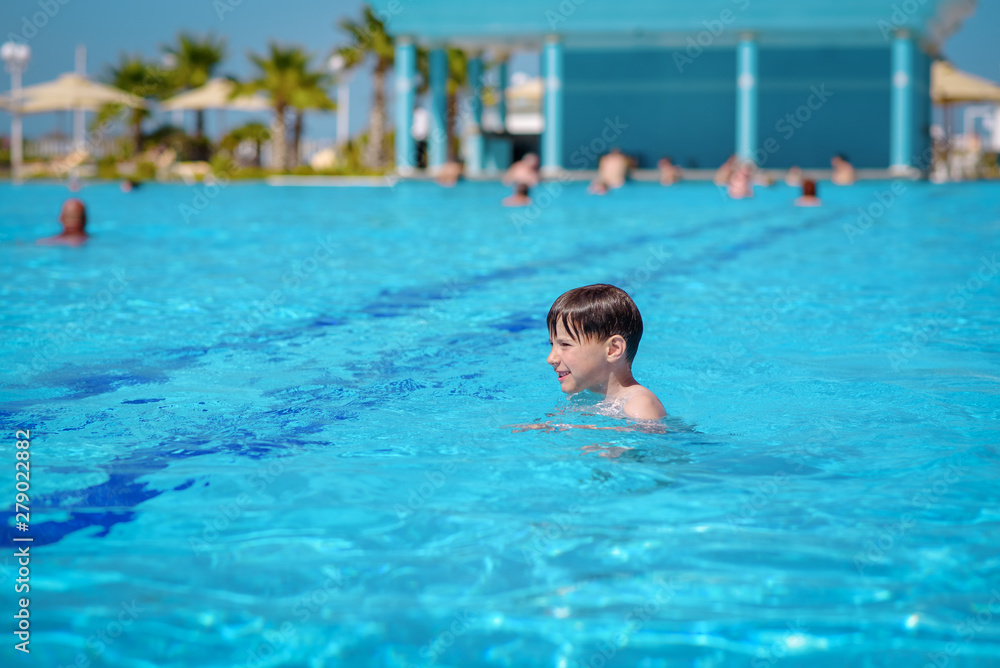 Caucasian boy swimming in pool on summer vacations.