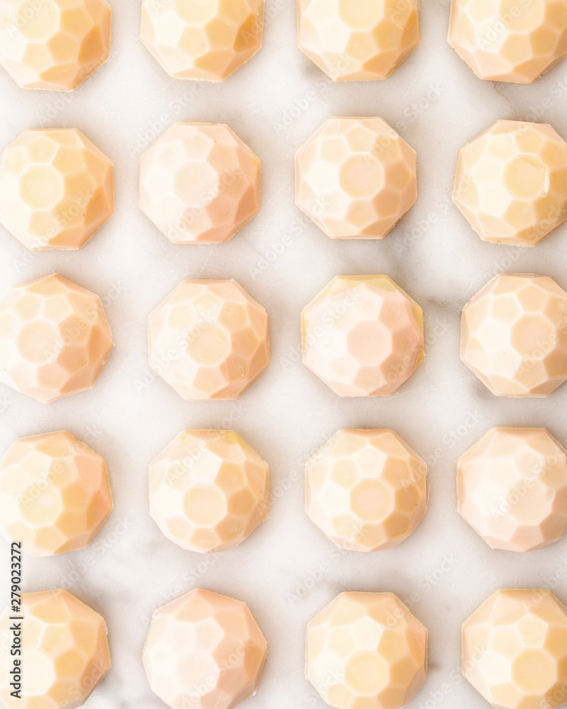 Exclusive handcrafted chocolate candy. Luxury handmade bonbon decorated with cream paint on white marble background. Product concept for chocolatier Exclusive handcrafted chocolate candy. Luxury handmade bonbon decorated with cream paint on white marble background. Product concept for chocolatier