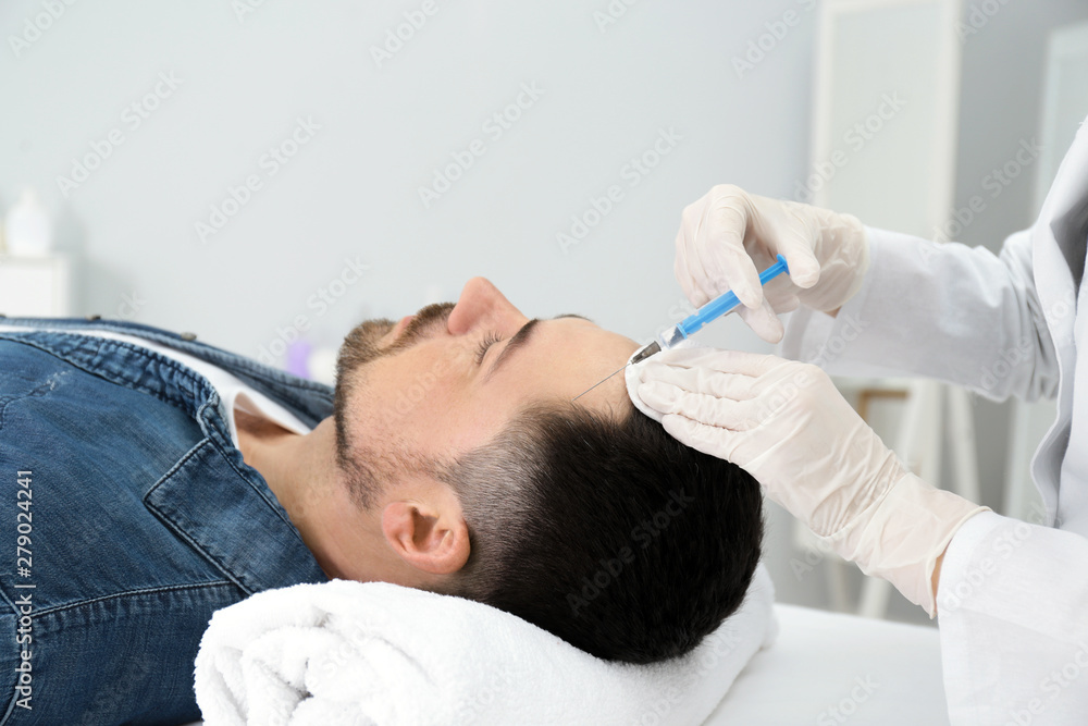 Man with hair loss problem receiving injection in salon Man with hair loss problem receiving injection in salon