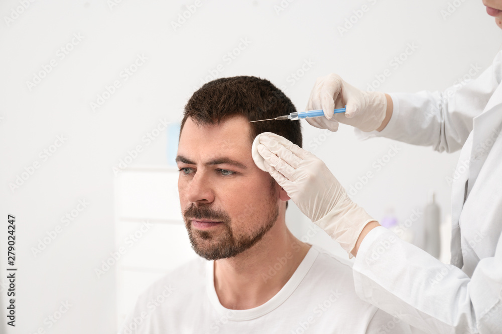 Man with hair loss problem receiving injection in salon Man with hair loss problem receiving injection in salon