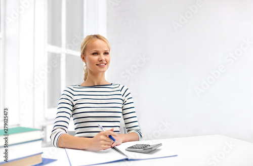 education  school and learning concept - student woman with books  notebook and calculator at home