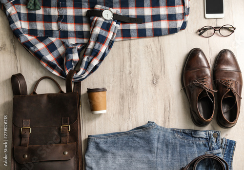 Flat lay composition with male outfit and accessories on wooden floor. Space for text
