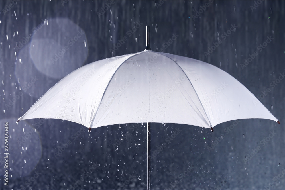 White umbrella under rain on dark background