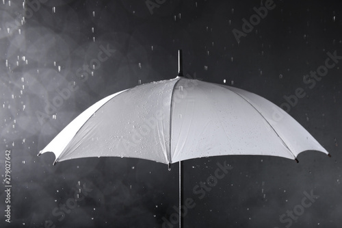 White umbrella under rain on dark background