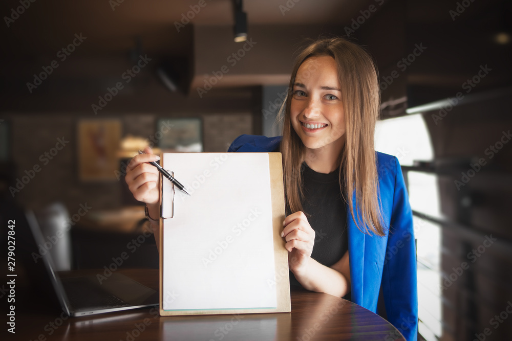 A beautiful woman with long hair is holding a banner, a sheet of paper and smiling, a place for text. A beautiful woman with long hair is holding a banner, a sheet of paper and smiling, a place for text.