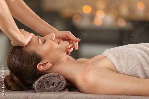 Beautiful young woman enjoying massage in spa salon photo