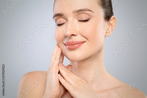 Portrait of beautiful young woman with perfect skin on grey background, closeup. Spa treatment