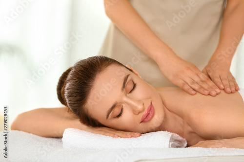 Beautiful young woman enjoying massage in spa salon