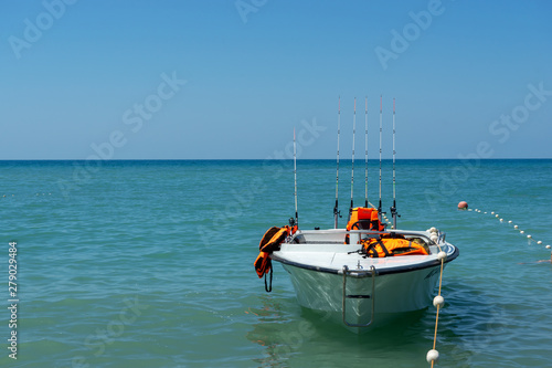 White fishing boat with fishing poles against the backdrop of the sea landscape. Sports boat at the pier.  © Elena Shi
