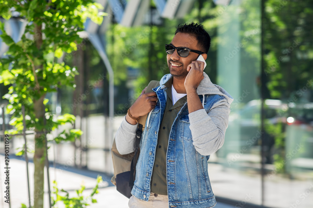 travel, tourism and lifestyle concept - smiling indian man with backpack calling on smartphone on city street travel, tourism and lifestyle concept - smiling indian man with backpack calling on smartphone on city street