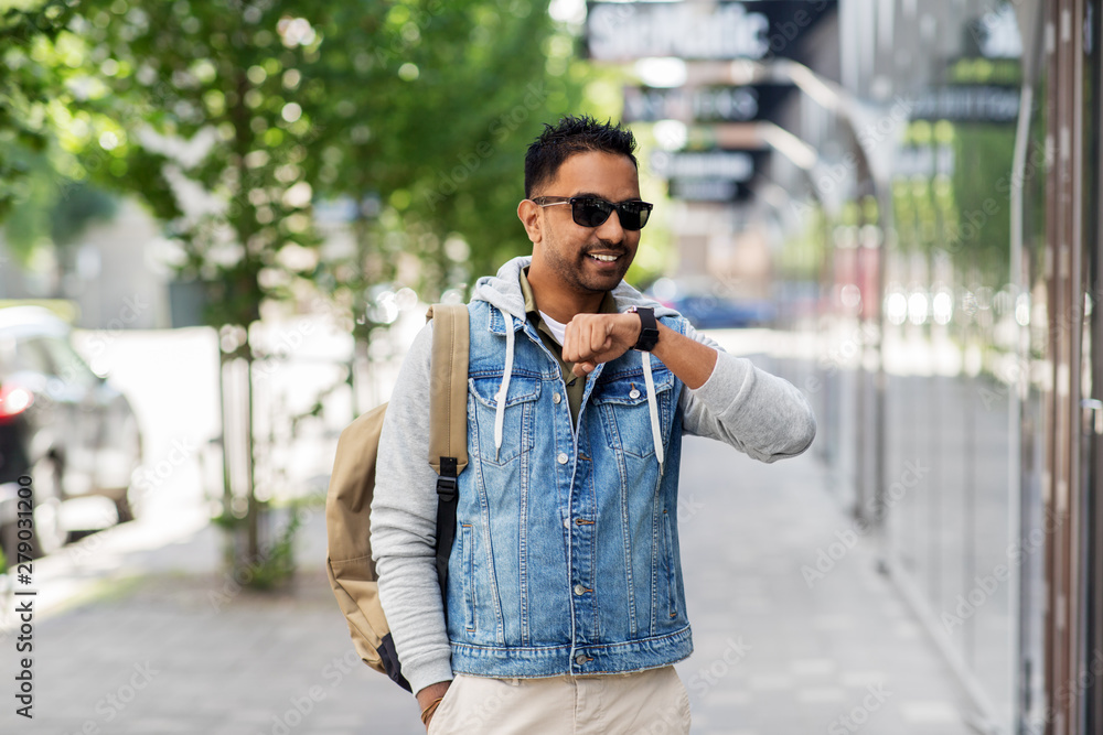 travel, tourism and lifestyle concept - smiling indian man using voice command recorder on smart watch on city street