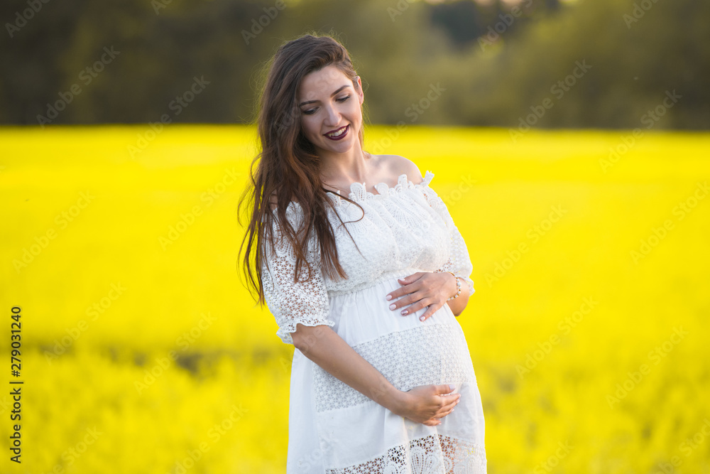 Pregnant girl on a yellow background. looks at his stomach, imagines his unborn child. Maternity concept Pregnant girl on a yellow background. looks at his stomach, imagines his unborn child. Maternity concept