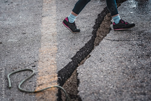 Girl jumping over the crack gap in the road