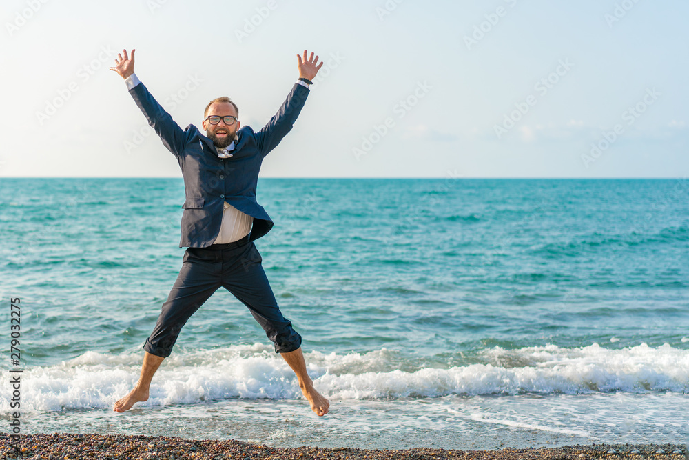 Happy businessman jumping on the beach. Man having fun by the sea. Summer vacation and travel concept Happy businessman jumping on the beach. Man having fun by the sea. Summer vacation and travel concept