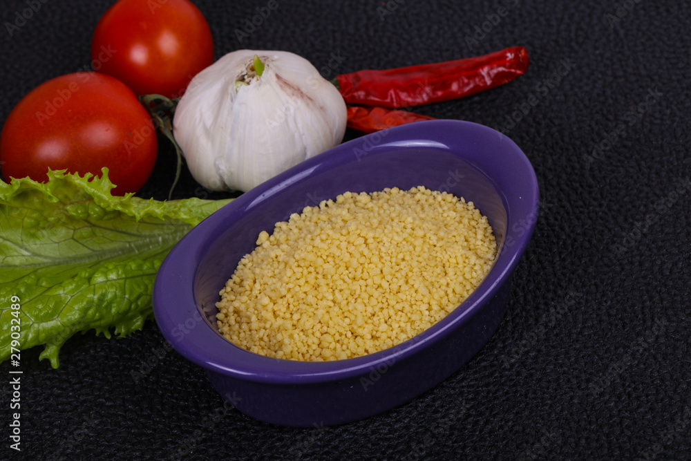 Raw couscous in the bowl served salad leaves, tomato and pepper Raw couscous in the bowl served salad leaves, tomato and pepper