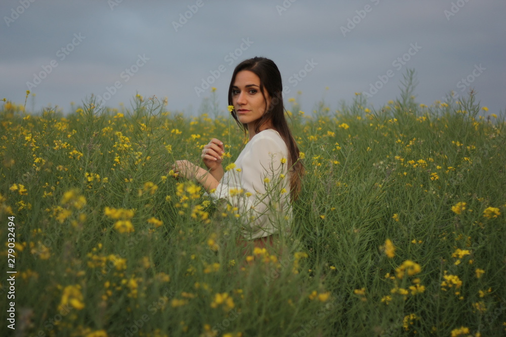 Beautiful woman on yellow flowers field with dark cloudy sky Beautiful woman on yellow flowers field with dark cloudy sky