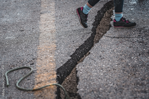Girl jumping over the crack gap in the road