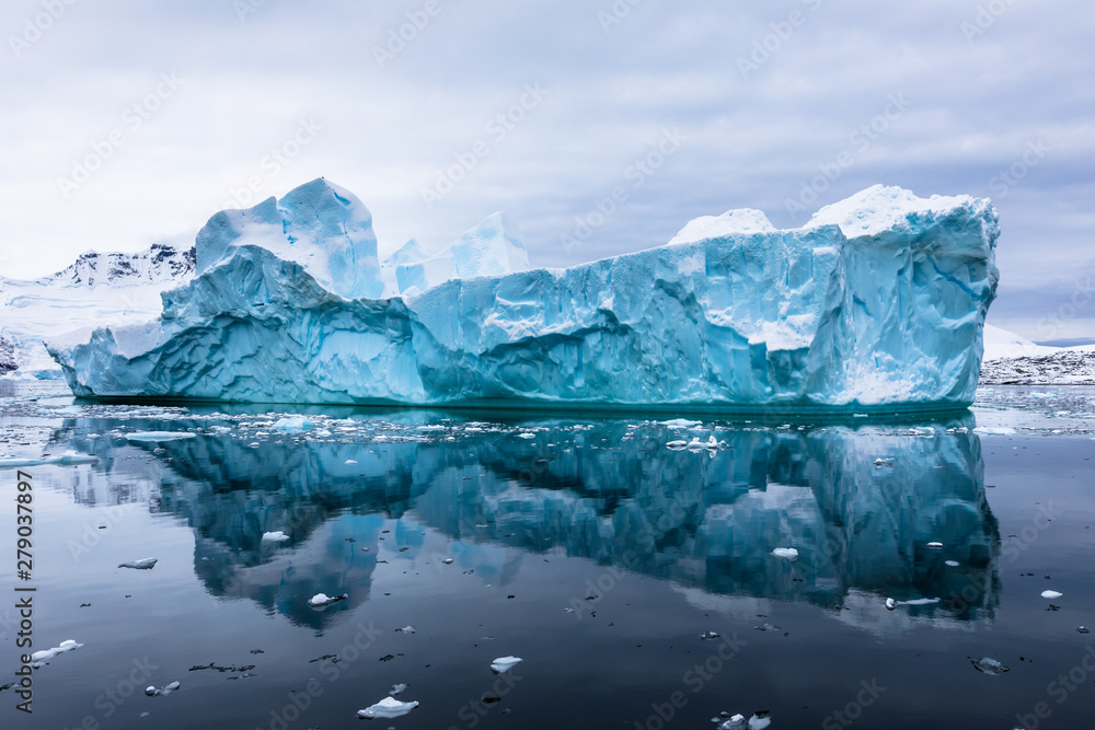 Impressive iceberg with blue ice and beautiful reflection on water in Antarctica, scenic landscape in Antarctic Peninsula