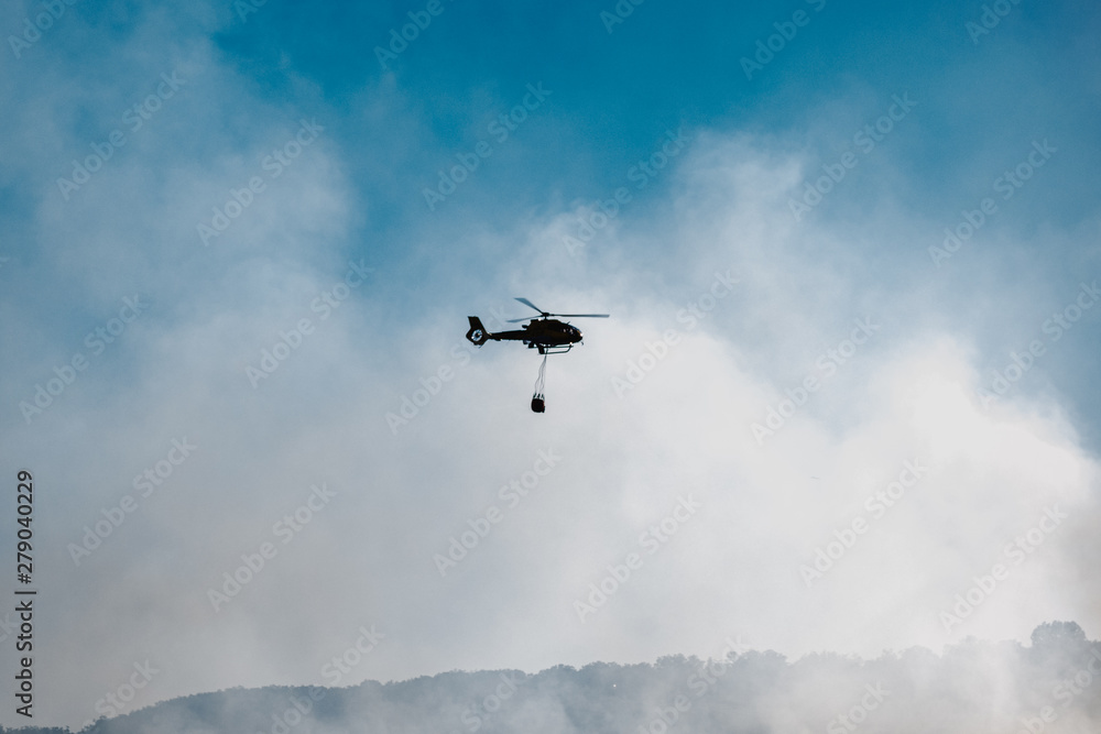 Helicopter launching water during a forest fire